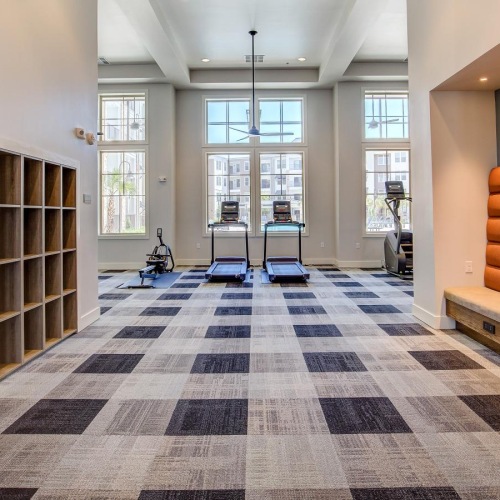 the entrance of a gym with carpet, lockers and treadmills